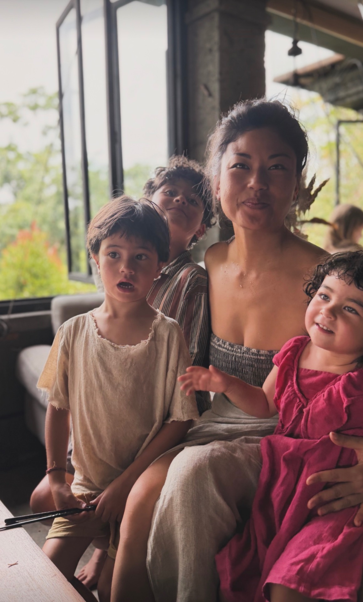 A mother with her three children gathered close in soft natural light